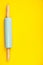 Blue rolling pin on yellow background, flat lay