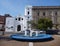 Blue round fountain in front of a white church