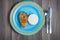 Blue round plate with red fish, rice, fork and knife on dark wooden background