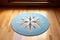 a blue rug with a compass design in the middle of a light-toned hardwood floor