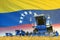 Blue rural agricultural combine harvester on field with Venezuela flag background, food industry concept - industrial 3D