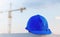 The blue safety helmet at construction site with crane background