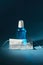 Blue sanitizer in a large bottle and a medical face mask. dark background