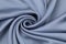 The blue satin fabric is laid out on the table in a spiral view. Soft folds of a drapery