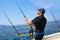 Blue sea fisherman in trolling boat with downrigger