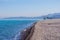 Blue sea, sea coast, small stones. Mountains in the distance