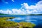 Blue sea water, the coast of the green lawn, the mountains in the distance, the green plants on the hills