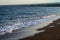 Blue sea water over volcanic sand beach. Relaxing sea wave surf over seashore.