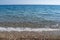 Blue sea water splashing on a gravel beach.