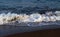 Blue sea water tide on dark volcanic beach. Relaxing sea wave surf over seashore.