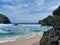 Blue sea white sand beach with beautiful towering hills and rocks