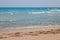 Blue sea with white waves and sand with footprints