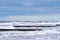 Blue sea with wooden breakwaters, blue cloudy sky, seascape