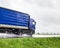 A blue semi-trailer truck drives on a wet highway during the rain in summer. The concept of poor visibility and traffic