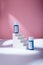 Blue serum or acid mock up bottles with blank label, no brand template on white concrete stairs, pink backdrop. Cosmetics hair