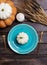 Blue serving plate with white baby squash on it, golden tableware, candle and wheat on wooden background