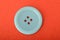 Blue sewing button isolated on a red background