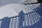 Blue shadows from a person leaning on a patterned fence against a white background of pure snow on a sunny winter day.