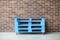 blue shipping pallets for sitting with weels on brick wall background