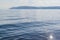 Blue siberian mountains on horizon in clear calm water surface of lake baikal, ripples, morning