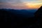 Blue silhouettes of Carpathian rocky mountains and sunset orange-blue sky with clouds