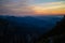 Blue silhouettes of Carpathian rocky mountains and sunset orange-blue sky with clouds