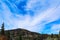 Blue sky above mountains, covered with trees. cirrostratus clouds