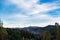 Blue sky above mountains, covered with trees. cirrostratus clouds