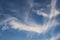 Blue sky background with big white tiny stratus cirrus striped clouds