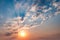 Blue sky background with evening fluffy curly rolling altocumulus altostratus clouds with setting sun. Good windy weather