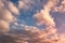 Blue sky background with evening fluffy curly rolling altocumulus altostratus clouds with setting sun. Good windy weather