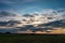 Blue sky background with evening fluffy curly rolling altocumulus altostratus clouds with setting sun. Good windy weather