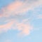 Blue sky background with pale pink clouds at sunset