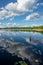 blue sky and cloud reflections in countryside lake in summer with boat and wooden boardwalk