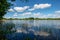 blue sky and cloud reflections in countryside lake in summer with boat and wooden boardwalk