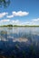 blue sky and cloud reflections in countryside lake in summer with boat and wooden boardwalk