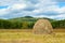 Blue sky and clouds over green hills with haystack