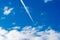 blue sky with clouds and plane trail