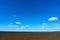 Blue sky with clouds and a plowed field