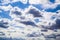 A blue sky with dramatic cumulonimbus clouds framed by silvery cumulus and cirrus clouds scattered across the sky