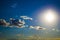 A blue sky with dramatic cumulonimbus clouds framed by silvery cumulus and cirrus clouds scattered across the sky