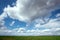 Blue sky with floating clouds, green field