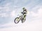 Blue sky, jump and man on motorbike in air for practice, training and extreme sports energy. Professional dirt biking