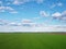 Blue sky over a green field, aerial view. Farmland landscape