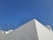 Blue sky over the roof of a white building of a brutalist building