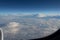 Blue sky in the porthole, white fluffy clouds below. Jet engine. Blue horizon, view from the airplane`s porthole.