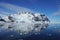 The blue sky shows radial clouds  icebergs and deep blue sea.