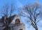 Blue sky With Some Mottled White Clouds Is backdrop for Bare Trees and Beautiful Building Top