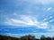 BLUE SKY WITH SWEEPING WISPY CLOUDS OVER GREEN VEGETATION