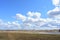 Blue sky. Thick clouds low over the ground. Forest in the distance. Green field of grass. The Kostroma River. A large field